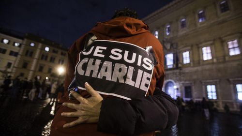 People embrace outside the French embassy in Rome, Italy during a tribute to the Charlie Hebdo victims. (AAP)