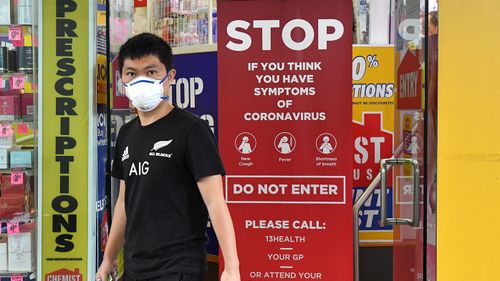 A customer wearing a protective face mask is seen leaving a pharmacy on Edward Street in Brisbane, Monday, March 23, 2020. (AAP Image/Darren England) NO ARCHIVING