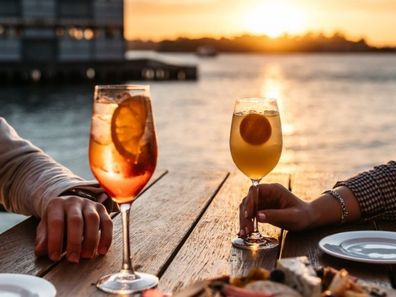 A couple enjoying a drink at sunset overlooking Sydney Harbour.