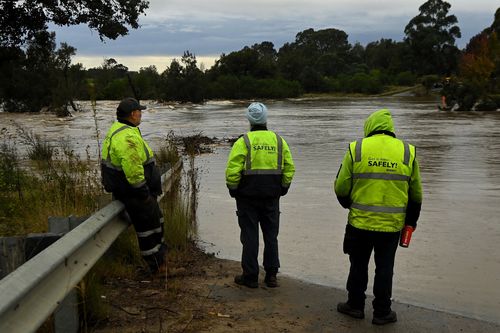 People looks at the Menangle bridge that crosses the Nepean River which is under water and where two cars were inundated by the rising flood waters . Menangle, NSW. June 7, 2024.  