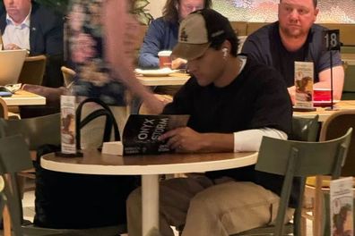 Actor Josh Heuston reading Onyx Storm at Sydney airport