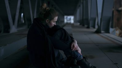 Caucasian woman sitting under bridge