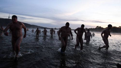 Participants of the Winter Solstice Nude Charity Swim get out of the waters of Lake Burley Griffin in Canberra. Picture: AAP