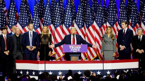 Former U.S. President Donald Trump, center, during an election night event at the Palm Beach Convention Center in West Palm Beach, Florida, U.S., Wednesday, Nov. 6, 2024. Trump is one step away from retaking the White House, projected as the winner in key swing states with his party set to control the Senate and markets swinging in anticipation of his possible victory. Photographer: Eva Marie Uzcategui/Bloomberg