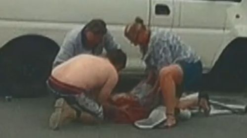 Bystanders cradled a man on the road after a car accident.