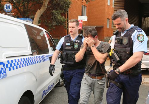 Police cuff and lead away a suspect during one of many raids carried out in the city before Christmas.