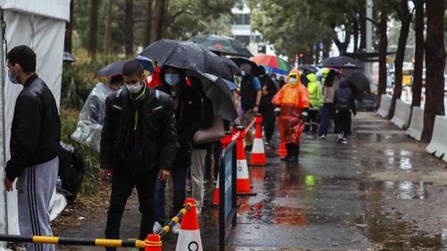 People line up to receive their covid-19 vaccination despite wet weather at the Sydney Olympic Park Vaccination Centre in Sydney.