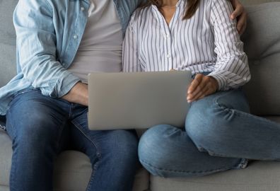 man and woman sitting on lounge looking at laptop screen