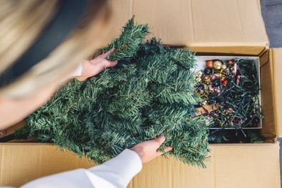 Young woman unpacking the Christmas Tree box and taking out the Christmas Tree 