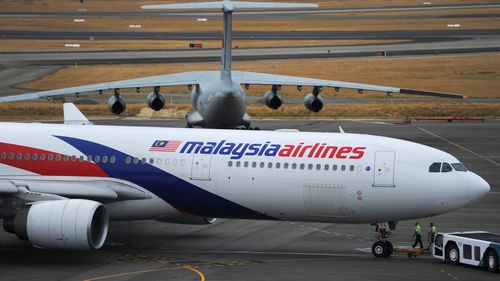 PERTH, AUSTRALIA - MARCH 25:  A Malaysia Airlines plane prepares to go out onto the runway and passes by a stationary Chinese Ilyushin 76 aircraft (top) at Perth International Airport on March 25, 2014 in Perth Australia.  The Australian Maritime Safety Authority has suspended the air and sea search for the missing Malaysian Airlines flight MH370 due to poor weather conditions in the search area. Search operations are expected to resume tomorrow.  (Photo by Greg Wood - Pool/Getty Images)