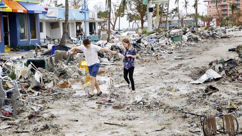 Jake Moses, 19, left, and Heather Jones, 18, of Fort Myers, explore a section of destroyed businesses at Fort Myers Beach, Florida, on Thursday, Sep 29, 2022, following Hurricane Ian 