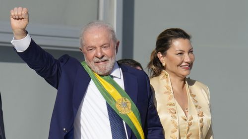 President Luiz Inacio Lula da Silva, left, waves to supporters as he holds hands with his wife Rosangela Silva at the Planalto Palace in Brasilia, Brazil, Sunday, Jan. 1, 2023. (AP Photo/Andre Penner)