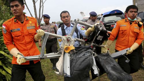 National Search and Rescue Agency personnel carry seats from AirAsia Flight 8501. (AAP)