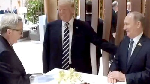 Donald Trump appears to pat Vladimir Putin on the back during their first face-to-face meeting. (Supplied)