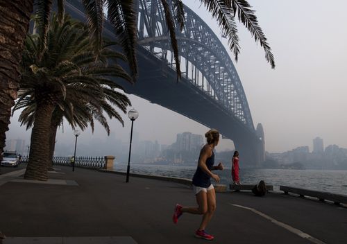 A jogger runs along the waterfront as smoke haze from bushfires sits over the harbour bridge.