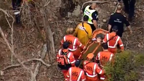 SES and police carry a woman out of Lerderderg state forest who had been missing for three days. (9NEWS)