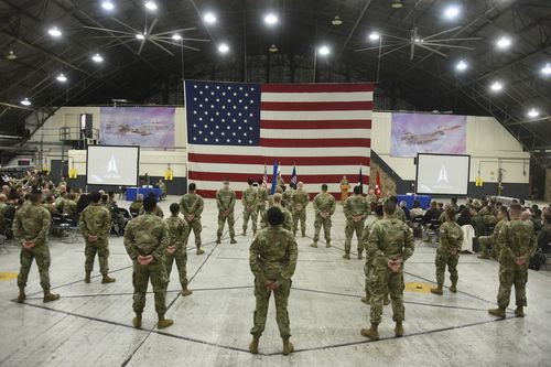 Des soldats américains debout dans une salle lors de la cérémonie d'activation des forces spatiales des États-Unis avec un drapeau américain devant eux