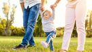 The first steps of the baby. Parents are teaching their child to walk. A happy family.