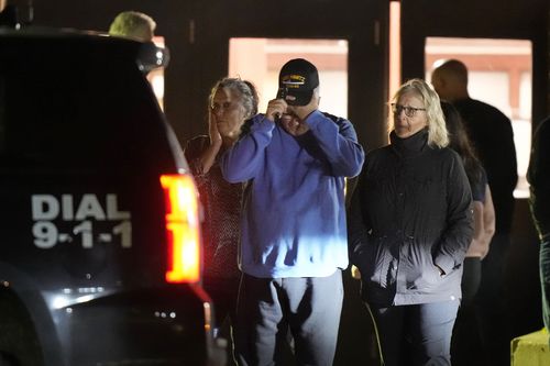 People depart a reunification center early Thursday, Oct. 26, 2023, at Auburn Middle School, in Auburn, Maine, after shootings in Lewiston.