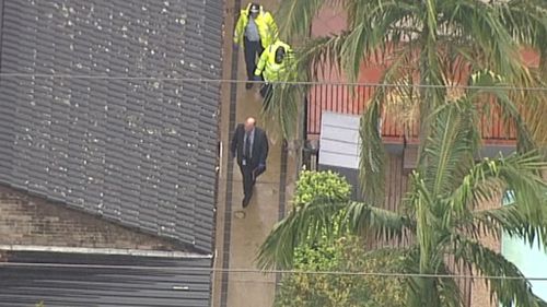 Investigators walk down a side path along the home on Sir Thomas Mitchell Drive. Source: 9News