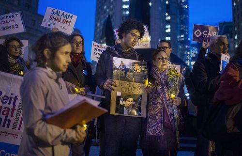  Bahij Chancey, 26, center, holds a photo of his friend and, one of the victims Nicholas Cleves, during an interfaith vigil for peace at Foley Square. (AAP)
