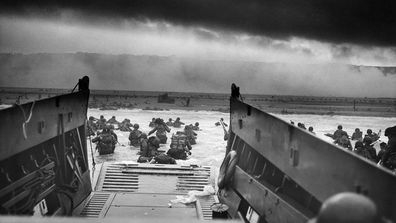 American troops wade ashore under heavy fire on Omaha Beach, Normandy, on June 6, 1944.