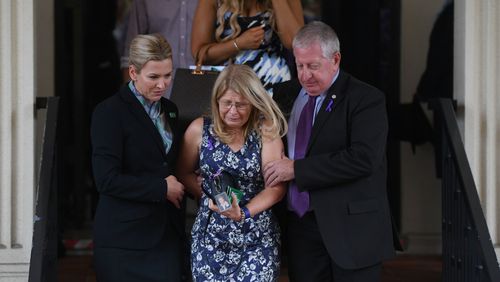 Faye Leveson is comforted by her husband Mark and a funeral director. (AAP)