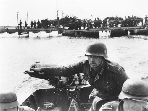 As the German invasion of the Ukraine continues, a German soldier is seen as he operates the outboard engine of a motorboat while crossing the Dnieper river, in September 1941. Standing in the  background are troops and military vehicles awaiting their turn. AP Photo)