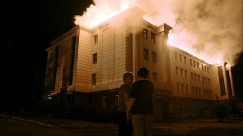 Bystanders watch a fire taking over a school in downtown Donetsk on August 27 after being hit by shelling. (Getty Images)