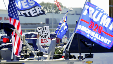 Joe Biden supporter Bill Morris from Middleburg directs his sign at the driver of a truck hauling a boat decorated with flags supporting President Donald Trump along Blanding Blvd. in Orange Park, Florida on Election Day Tuesday November 3, 2020. [Bob Self/Florida Times-Union via AP]