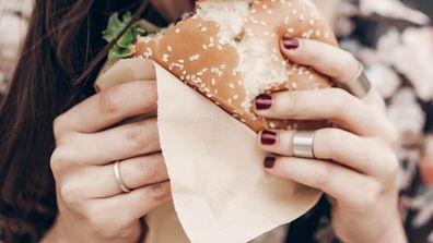 woman eating hamburger with beetroot