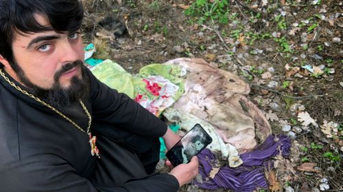 Father Vasyl Bentsa matches photos he made when he discovered the bodies of five men tortured and shot by Russian troops in Zdvyzhivka, Ukraine, including Mykola "Kolia" Moroz, 47, with potential evidence of the crime left in the forest where the men were buried.