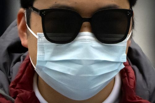 Un navetteur portant un masque facial conduit un scooter dans une rue du quartier central des affaires de Pékin, le vendredi 28 octobre 2022. 