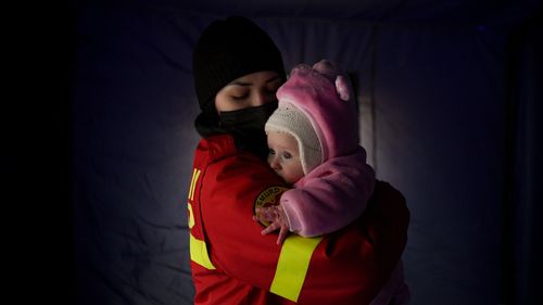 An employee from the Emergency Situation Inspectorate soothes the crying baby of a family fleeing the conflict from neighbouring Ukraine at the Romanian-Ukrainian border, in Siret, Romania.