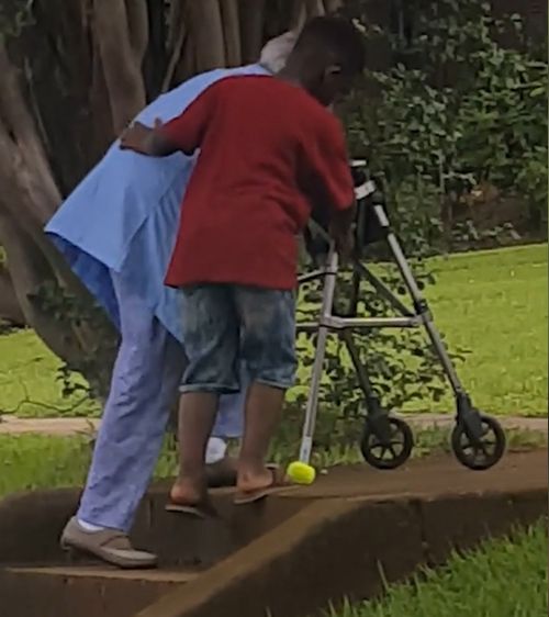 Maurice jumped out of his mother's car and stopped traffic to help this woman and her walking frame climb a set of stairs. Picture: Facebook.