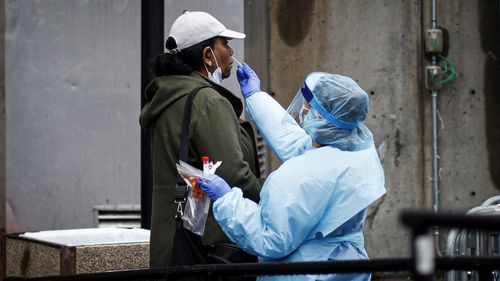 A patient is given a COVID-19 test by a medical worker outside Brooklyn Hospital Center, Sunday, March 29, 2020, in Brooklyn borough of New York. 