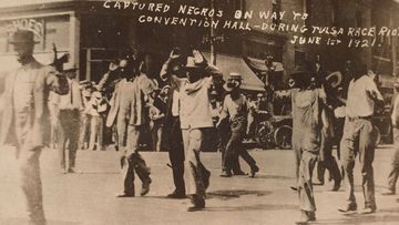 Men walk with their hands raised during the Tulsa massacre on June 1, 1921. Image is the gift of Cassandra P. Johnson Smith