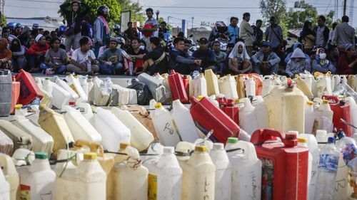 People sit as they queue for fuel at a gas station in Palu, Central Sulawesi, Indonesia after the powerful earthquake and tsunami.