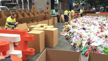 Volunteers have arrived at Martin Place to begin collecting some 100,000 bouquets estimated to populate the makeshift shrine. (ninemsn/Hal Crawford)