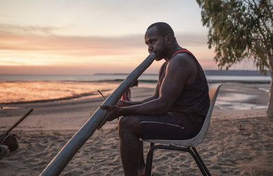 Local Aboriginal man play didgeridoo on the beach. Journey into East Arnhem Land, Northern Territory