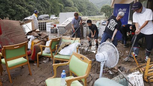Workers try to clean their nursing home following a heavy rain in Ashikita town, Kumamoto prefecture, southern Japan Saturday, July 4, 2020