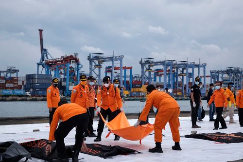 Indonesian search and rescue personnel carry body bags with human remains and debris from Sriwijaya Air flight SJ182 to be examined by investigators