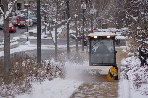 A worker clears a sidewalk of snow and ice after a weekend winter storm in Washington.