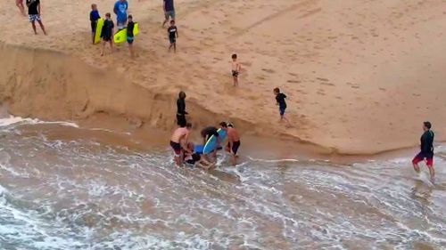 A group of Dee Why surfers have been hailed "heroes" after saving a man being swept out to sea during the city's wild weather.