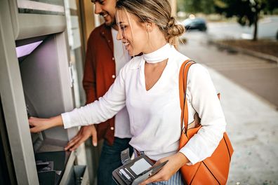 Young couple using ATM machine to withdraw money from credit card