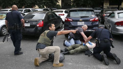 Members of the Department of Homeland Security and the US Marshal's Service tend to the downed shooter after shots were fired.