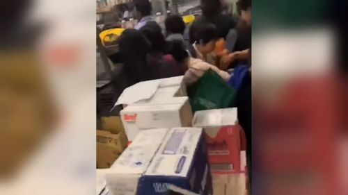 Shoppers scramble over each other to get to the tins of baby formula.