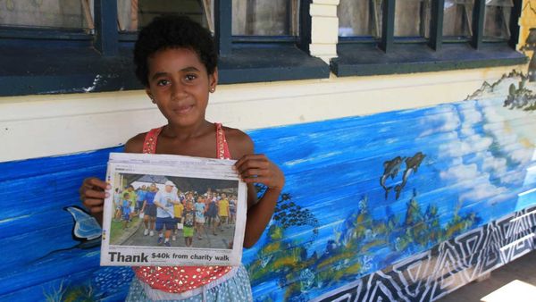 Student holds up newspaper article for Outrigger Fiji Beach Resort walkathon