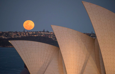 A super moon rises above the skyline behind the Sydney Opera House on September 28, 2015.