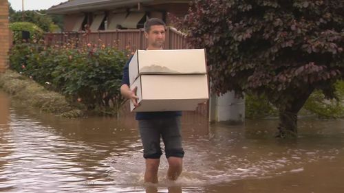 Une famille a pataugé dans les eaux de crue pour récupérer des objets de leur maison.